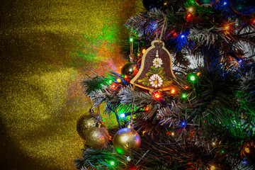 Close up detail of a plastic christmas tree with lit led garland and golden glitter background