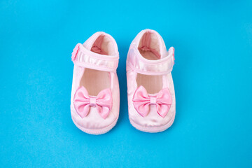 Pair of new born pink shoes flat lay on blue background, close up