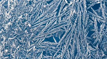 Close-up of blue frosty glass covered with sharp, sparkling ice crystal patterns. 