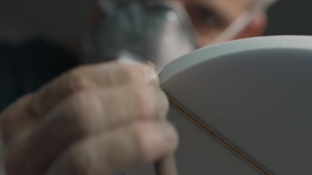 Surf board factory. Adult male shaper creates the surfing board on the factory