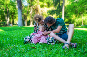 Fototapeta premium A man and a woman are sitting on the grass with a baby