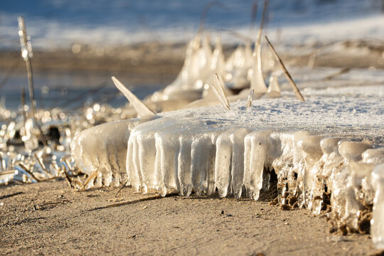 Thick ice slabs on the sandy shore of a lake, small icicles forming along the edges of the floes, capturing winter patterns in Central Germany.