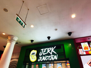 Naklejka premium Jerk Junction signboard inside a green Manchester restaurant in the UK, bright neon branding