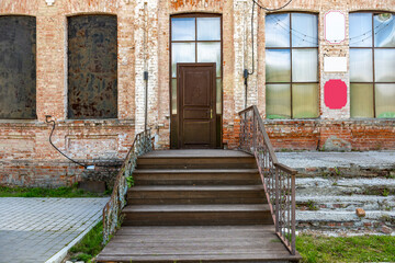 Elements of the weathered facade of an old building with preserved brickwork. A dilapidated porch....