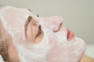Naklejka premium Young caucasian female relaxing with a facial mask for skincare rejuvenation and relaxation.