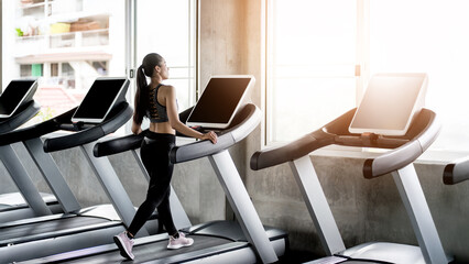 A beautiful young woman with a smiling face is in a gym. The concept is about exercise and health care. (Horizontal and vertical images available).