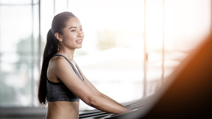 A beautiful young woman with a smiling face is in a gym. The concept is about exercise and health care. (Horizontal and vertical images available).