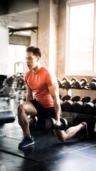 A young man exercises by lifting dumbbells at the gym to maintain his health.