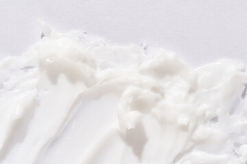 Smooth white cream texture on white surface for skincare or cosmetic product background.