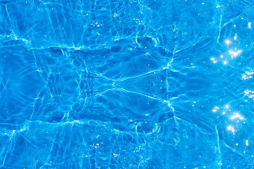 Blue water with ripples on the surface. Defocus blurred transparent blue colored clear calm water surface texture with splashes and bubbles. Water waves with shining pattern texture background.