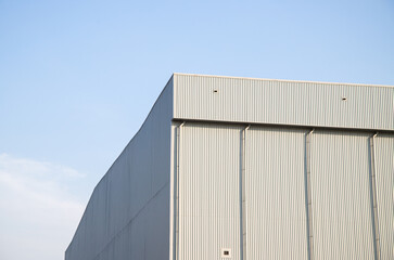 Warehouse Factory Industry Building with Geometric Metal Corrugated Steel Wall and Rooftop against Blue Sky Background, Modern Industrial Exterior Architecture Backdrop Structure in Minimal Style