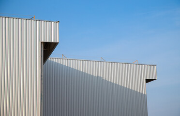Warehouse Factory Industry Building with Geometric Metal Corrugated Steel Wall and Rooftop against Blue Sky Background, Modern Industrial Exterior Architecture Backdrop Structure in Minimal Style