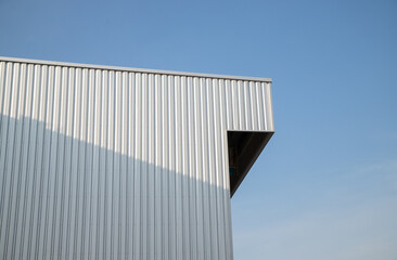 Warehouse Factory Industry Building with Geometric Metal Corrugated Steel Wall and Rooftop against Blue Sky Background, Modern Industrial Exterior Architecture Backdrop Structure in Minimal Style