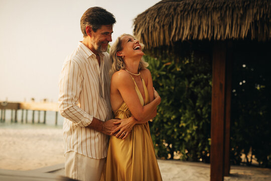 Happy couple laughing and embracing at a tropical beach resort