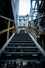 Staircase in a building with a yellow railing. The stairs are very long and the railing is yellow