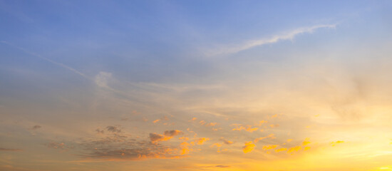 Fototapeta premium Golden Hour Sunset Sky with Soft Clouds and Blue Gradient,Beautiful sunset sky with a natural gradient from deep blue to vibrant golden yellow. Soft, wispy clouds scattered across the horizon during.