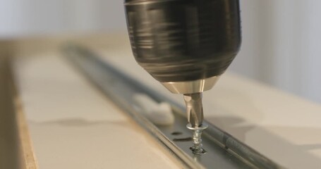 Man inserts screw into slot of sliding drawer system and tightens using screwdriver. Controlled movement ensures reliable fixation along with correct alignment