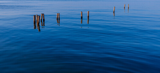 Minimalist Wooden Poles in Calm Blue Sea at Twilight,A serene and minimalist landscape featuring...