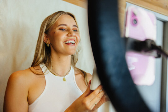 Young woman recording video content using smartphone and ring light for social media