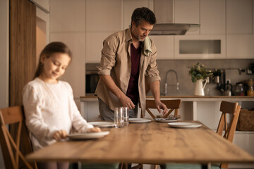 Father and daughter setting table for family lunch