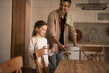 Fototapeta premium Father and daughter setting table for family lunch