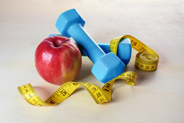 Dumbbells, apple and a tape measure for health, weight loss and fitness, healthy lifestyle concept,...