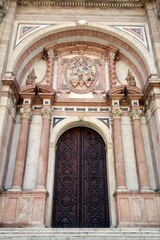 Obraz premium Detailed view of the main Baroque style facade and entrance portal of the Incarnation Cathedral in Malaga, Spain with marble columns and a relief of the Annunciation above the central door