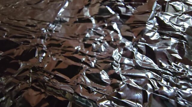 Close-up of silver crumpled foil with neutral white lighting, emphasizing the raw metallic texture and intricate folds