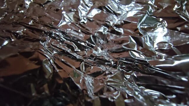 Close-up of silver crumpled foil with neutral white lighting, emphasizing the raw metallic texture and intricate folds