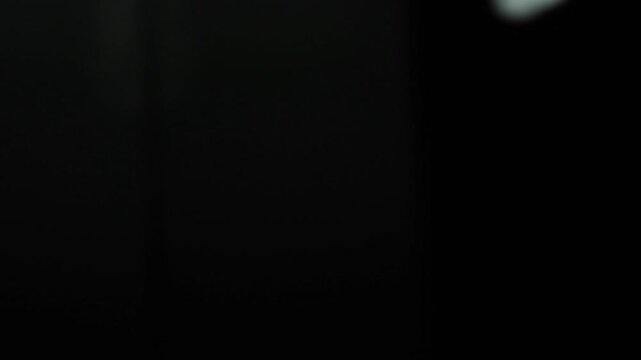 Primer plano de una luz de una lampara con un bombillo de color blanco en movimiento en la oscuridad. C&aacute;mara en movimiento