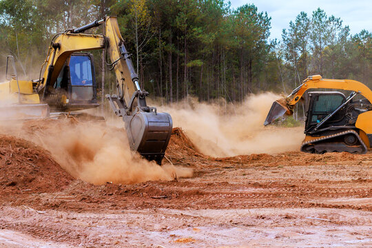Heavy bulldozer equipment excavator clears land on construction site, creating dust preparing for future building