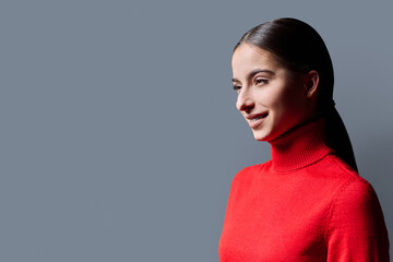 Profile portrait of young smiling woman on gray background © Valerii Honcharuk