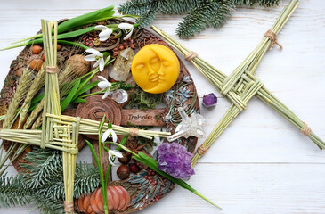 Wiccan altar for Imbolc sabbat. witchcraft, pagan magic ritual. Brigid's cross, crystals, wheel of the year, snowdrops, moon amulet on wooden table. symbol of Imbolc holiday, spring equinox. flat lay