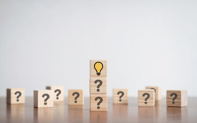 Creative Idea Lightbulb Icon on Wooden Cube Standing Out Among Question Marks for Problem Solving Concept