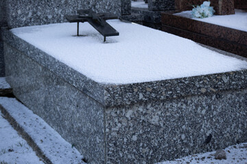 Granite tombstone covered in fresh white snow