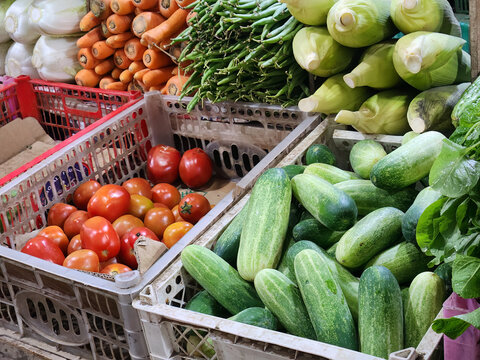 Fresh cucumbers and tomatoes in crates at vegetable market stall. Mixed produce display for grocery shopping and cooking content. Organic vegetables assortment for healthy diet promotion photo.