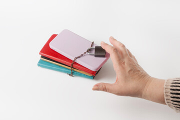 A hand reaches for a stack of cell phones, chained and locked. Information overload, digital fatigue, digital detox