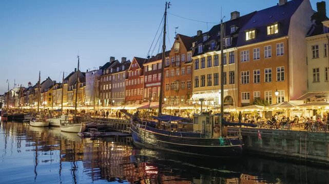 Night view of Nyhavn harbor in Copenhagen with smooth camera slide, illuminated historic buildings and calm Scandinavian city atmosphere, cinematic travel footage in 4K