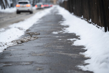 Asphalt sidewalk near roadway in city area covered with snow and technical salt, special substances...