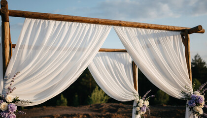 A minimal wedding ceremony arch with white fabric draping and light floral accents