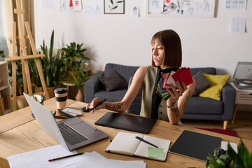 Creative young woman working at home on modern design projects with colorful materials