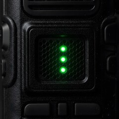 Glowing Green LED Indicator Lights on a Textured Black Electronic Device with Hexagonal Grid