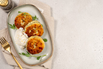 Crispy potato cakes served on a plate with yogurt and greens in a dining setting during daytime