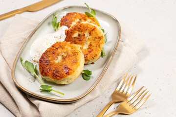 Crispy potato cakes served on a plate with yogurt and greens in a dining setting during daytime