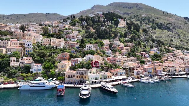 Aerial drone cinematic video of picturesque seaside main town and port of Yialos of Symi island with colorful neoclassical houses and traditional character, Dodecanese, Greece