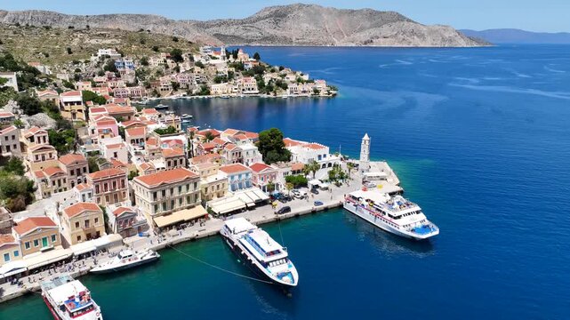 Aerial drone cinematic video of picturesque seaside main town and port of Yialos of Symi island with colorful neoclassical houses and traditional character, Dodecanese, Greece