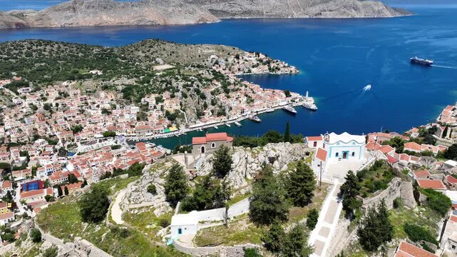 Aerial drone cinematic video of iconic castle of Symi island built uphill overlooking main town and Yalos, Dodecanese, Greece