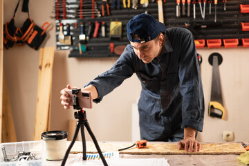 Professional carpenter in workshop recording video for social media and streaming live working process