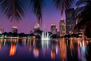 Fototapeta premium Modern city skyline with fountain and reflections at twilight