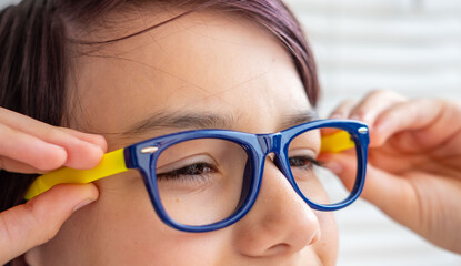 teenage boy wearing blue eyeglasses, touching frames, clear vision, eyesight correction, medical optics, Focus and clarity, childhood health, first glasses experience, Childhood and education